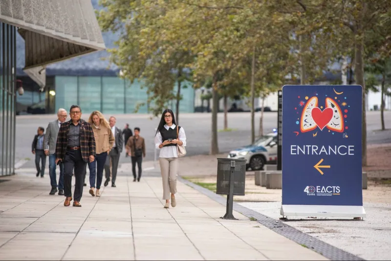 Participantes caminham junto à sinalização de entrada do 40º EACTS