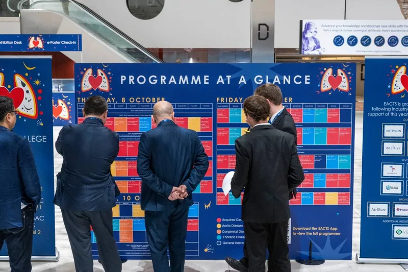 Participantes consultam o painel de programação do EACTS